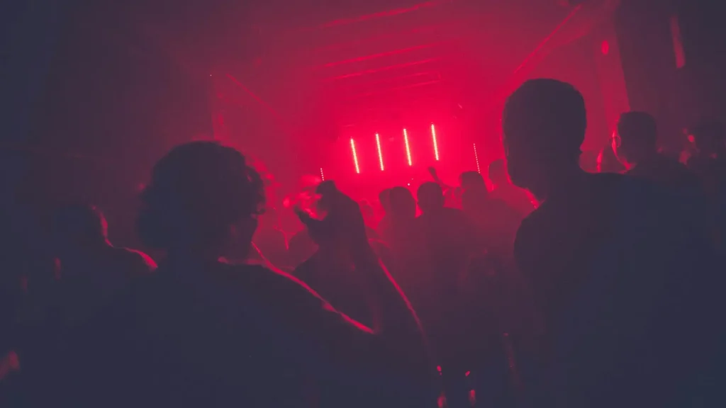 Personas bailando bajo luces rojas en una sala