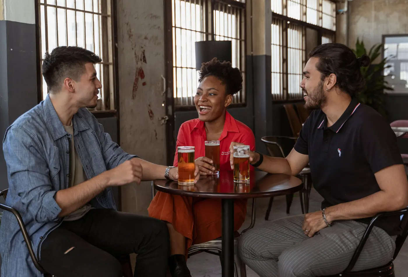 Three travellers talking and laughing around a table in a bar